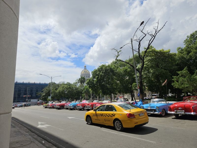 Modernes Taxi vor klassischen Oldtimern